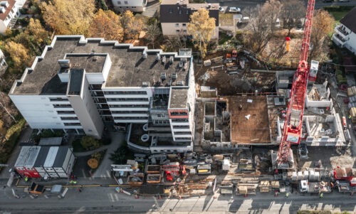 Luftaufnahme der Baustelle mit rotem Kran auf der rechten Seite