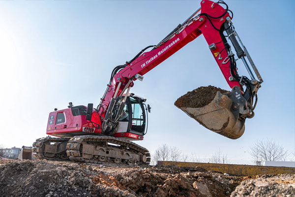 roter Bagger mit der Schaufel voller Erde