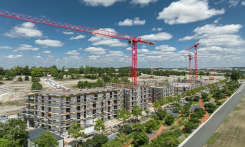 Seitenaufnahme des kompletten Geländes der Baustelle Wohnanlage Hubland zwei mit drei roten Kränen