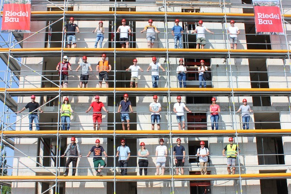 30 Personen stehen auf einem Gerüst auf einer Baustelle