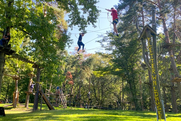 zwei Personen balancieren auf einem Seil im Kletterwald