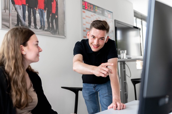 Junger Mann zeigt junger Frau etwas auf dem PC