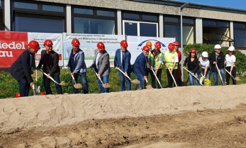 14 Personen haben eine Schaufel mit Sand in der Hand