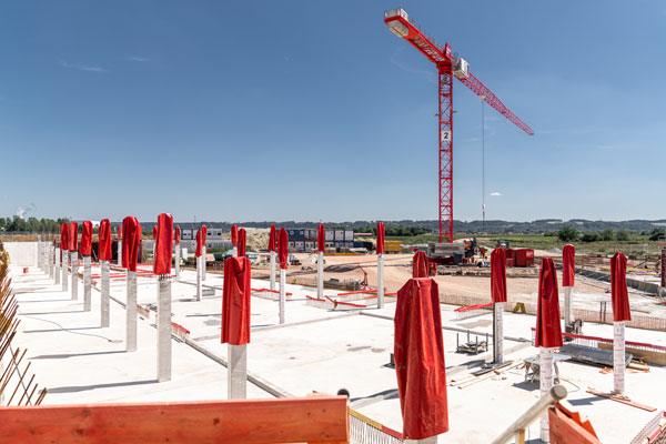 viele Betonsäulen mit roten Abdeckungen und ein roter Kran