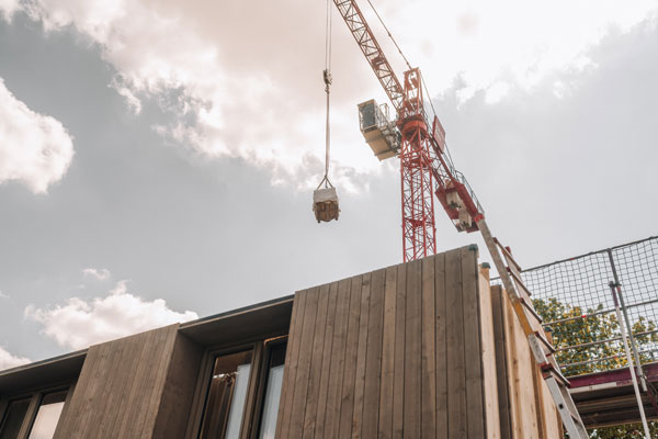 Baustelle mit Kran und Holzfassade