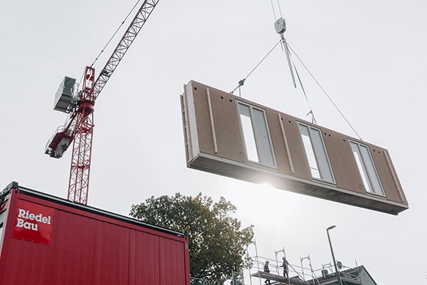 Kran hebt ein vorgefertigtes Holzbau-Modul in Position